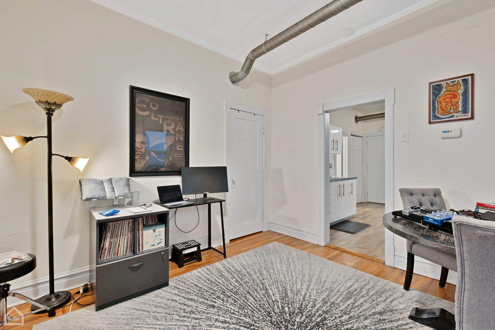 Living and dining area with hardwood floors, exposed ductwork, and an adjoining kitchen.