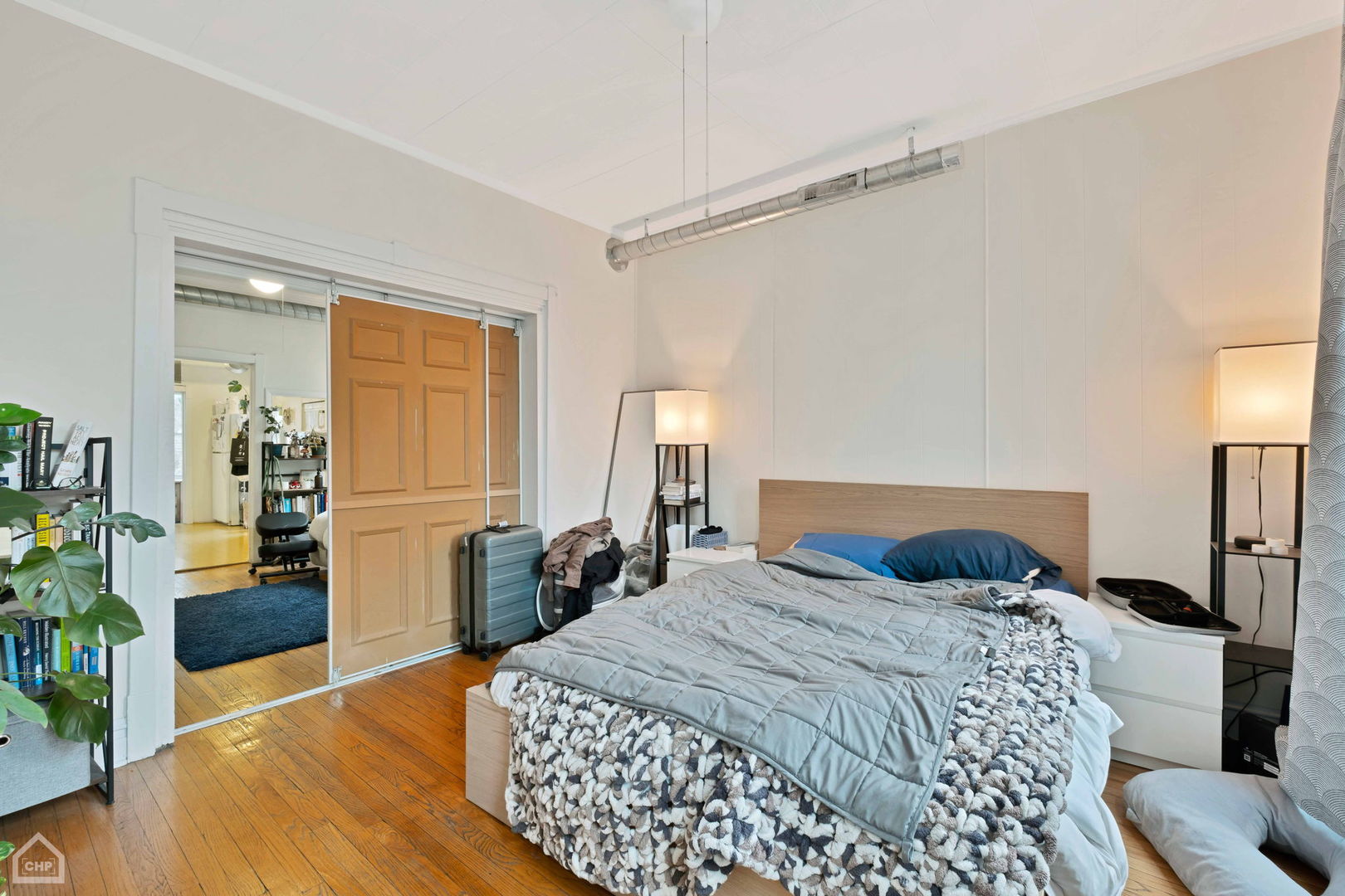 Bedroom with a large bed, hardwood floors, and paneled sliding doors.