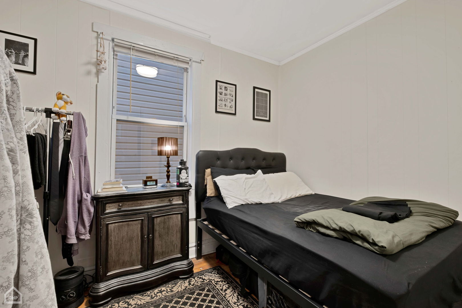Bedroom with a black bed, tufted headboard, and dark wooden cabinet beside a window.