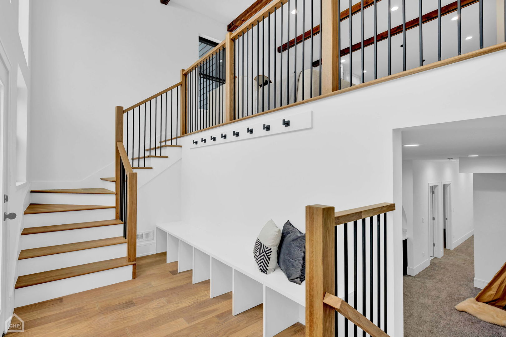 Modern staircase with wood treads and black balusters beside a built-in bench.