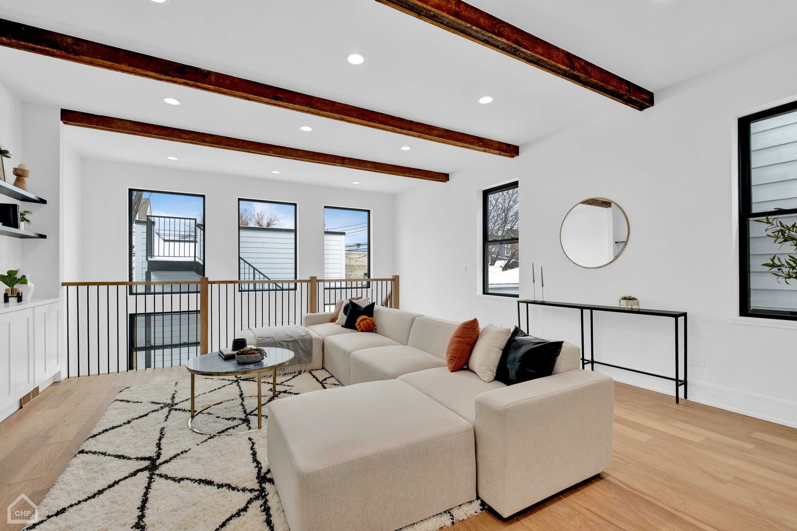 Living room with cream sectional, exposed wood ceiling beams, and windows overlooking snow.