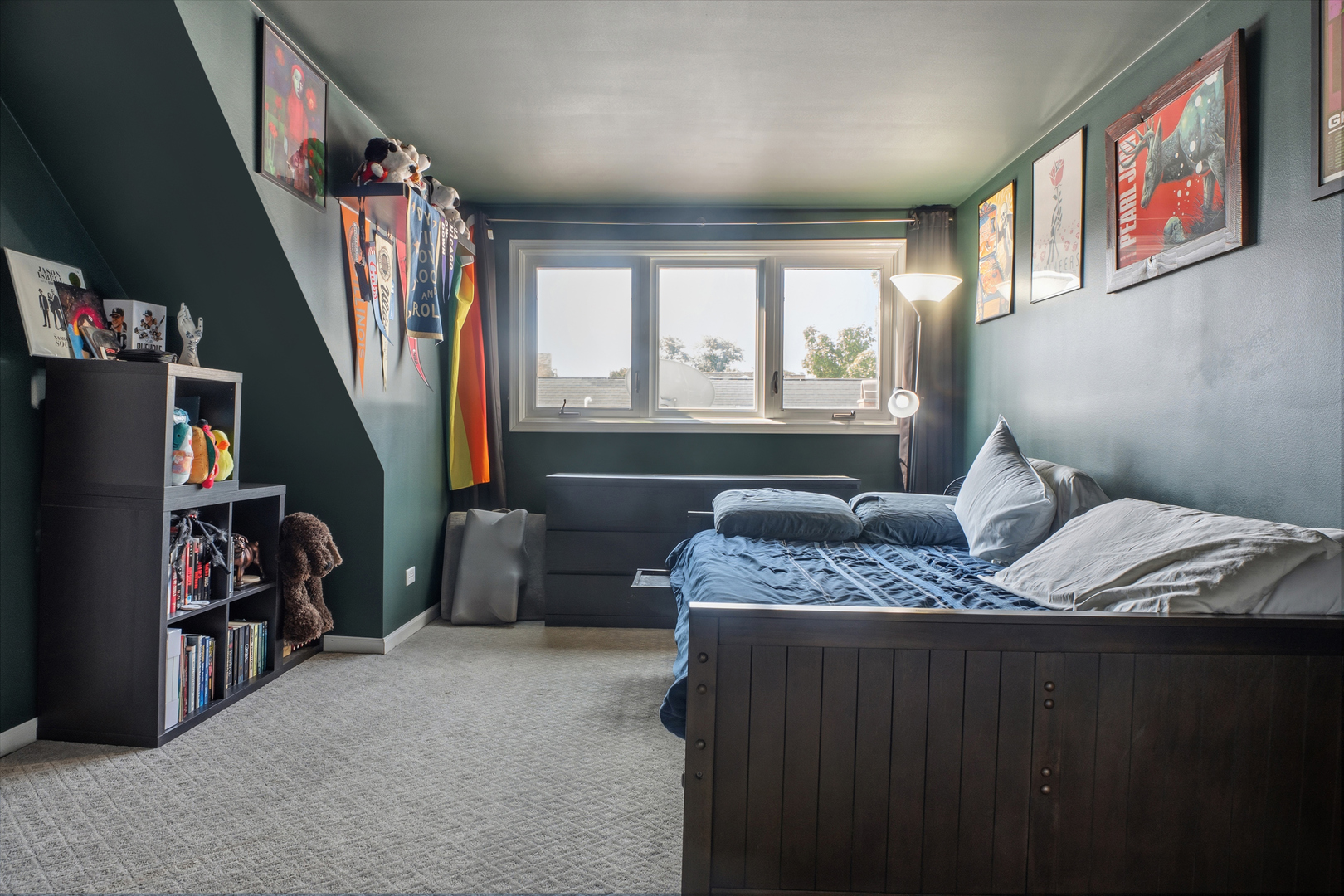 Bedroom with a dark wood bed, blue bedding, green walls, and sports memorabilia.