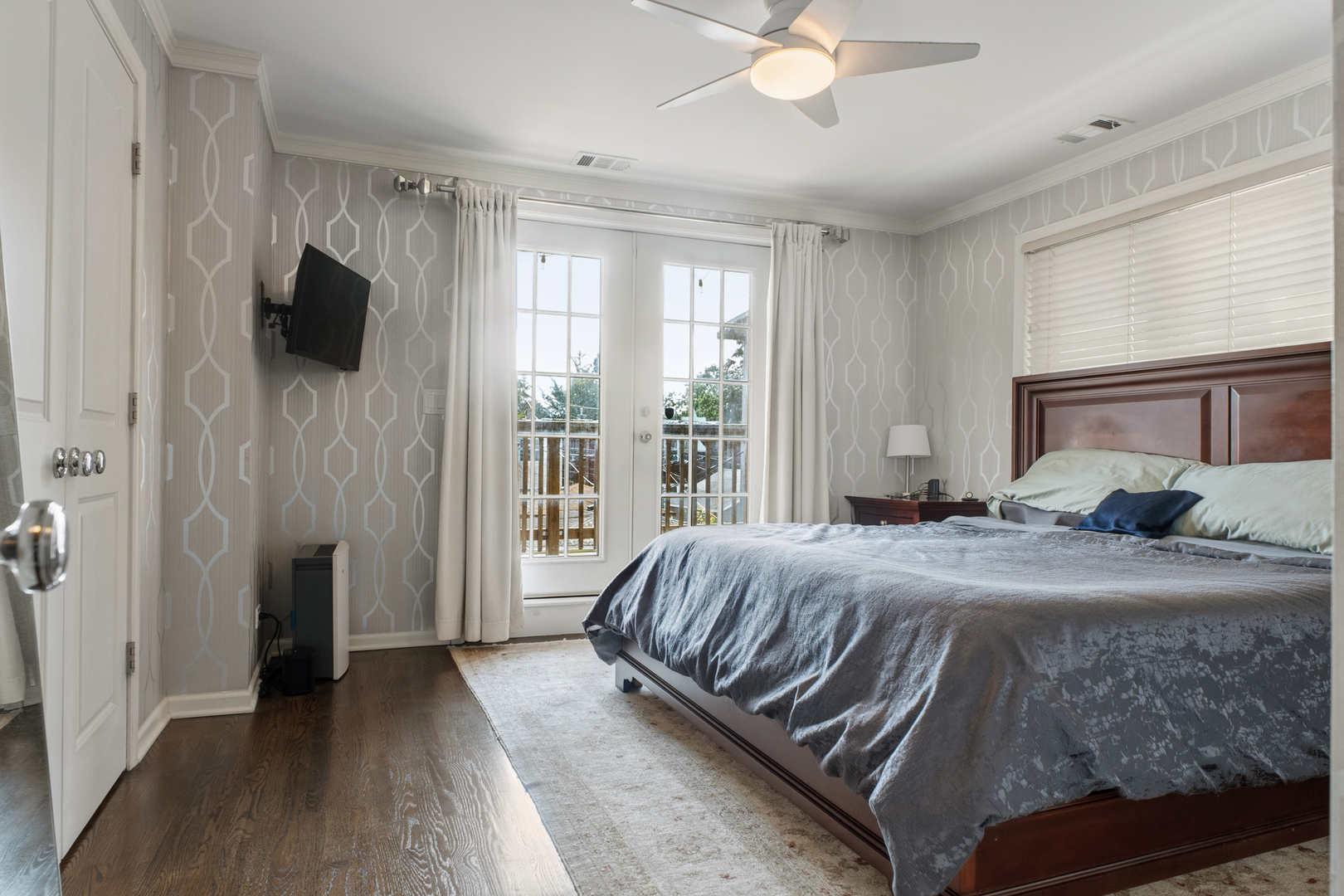 Bedroom with a large wooden bed and French doors opening to a balcony