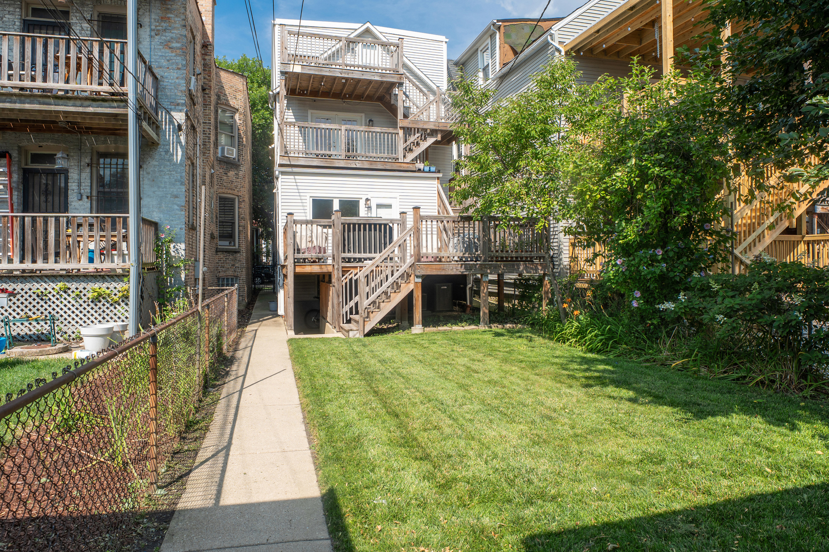 Home’s rear exterior with multi-level wooden decks, stairs, and a grassy backyard.