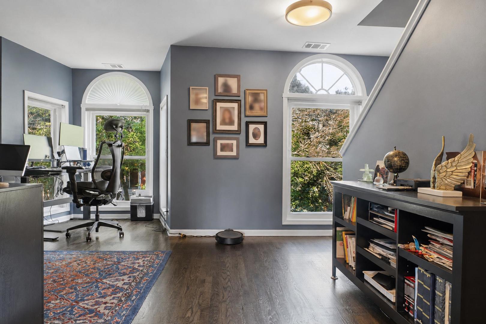 Home office with arched windows, a desk, and a black bookcase.