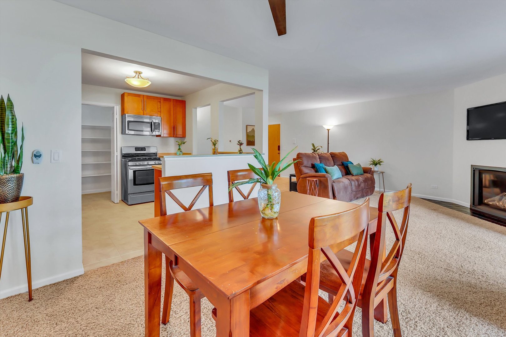 Dining area with a wooden table overlooking the kitchen and living room with a fireplace.