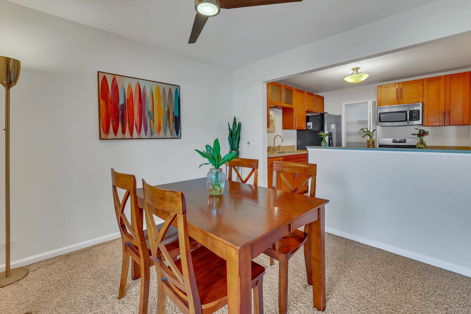 Dining area with a wooden table and chairs opening to a kitchen with orange wood cabinets.