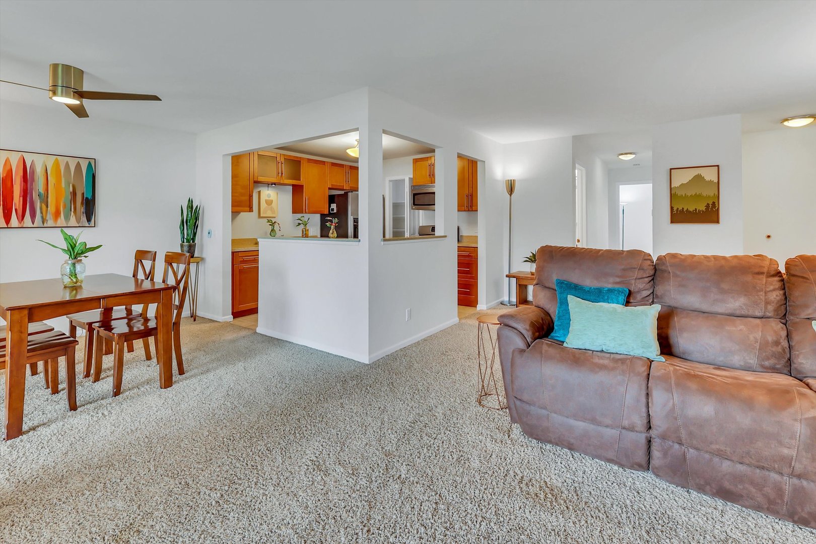Furnished living and dining area with a brown sectional, wooden dining set, and open kitchen with warm cabinetry.
