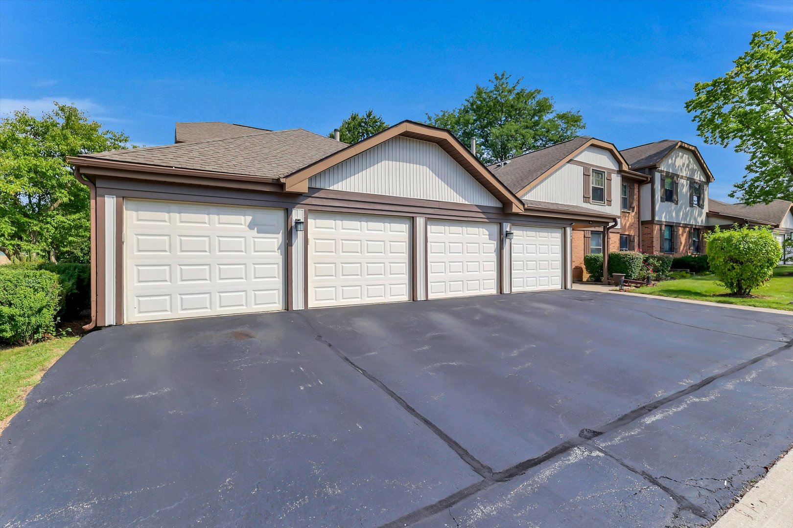 Attached townhomes with white garage doors and a broad asphalt driveway.