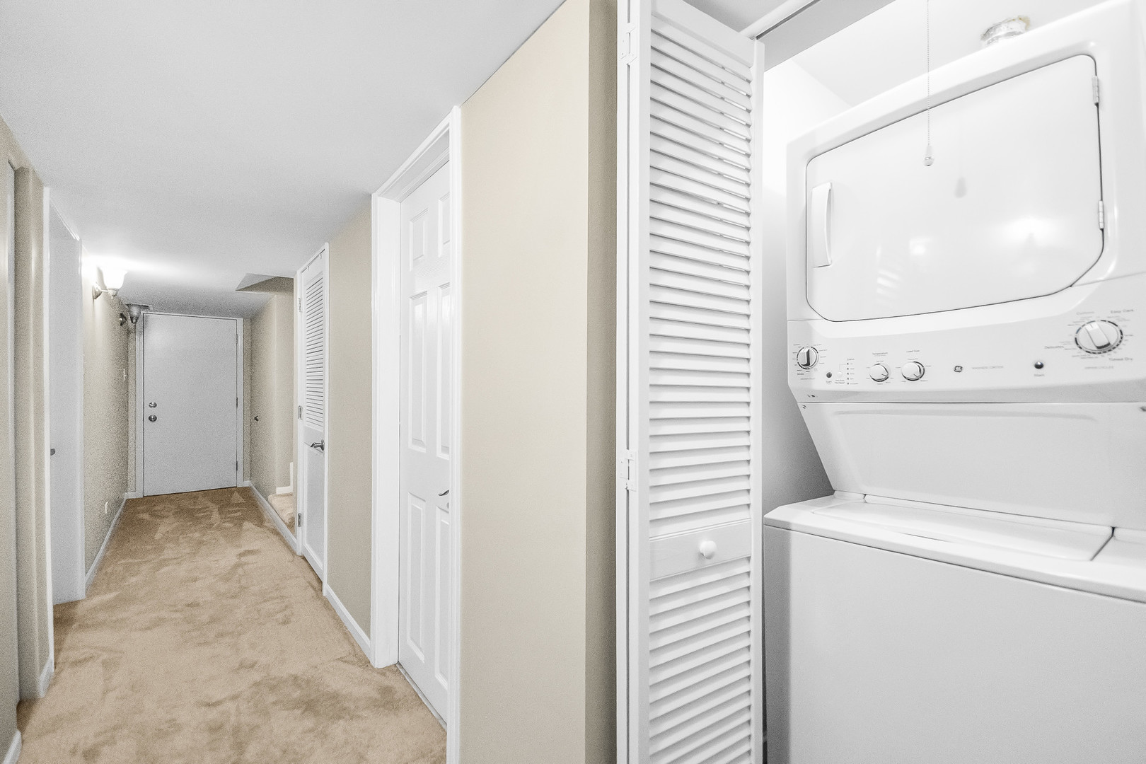 Hallway with a stacked washer and dryer in an open laundry closet.