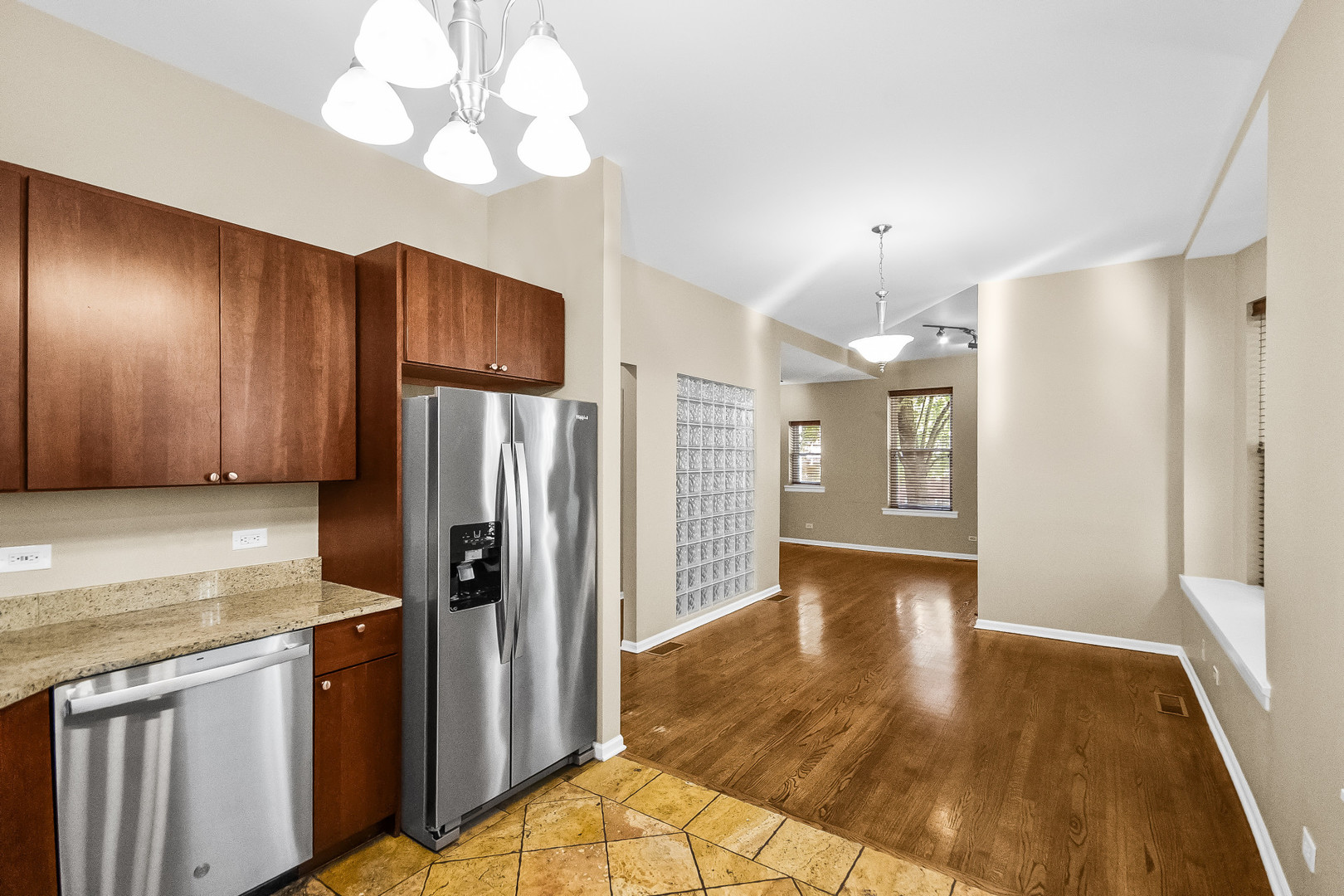 Kitchen with dark wood cabinets and stainless steel appliances opening onto a hardwood-floored living area.