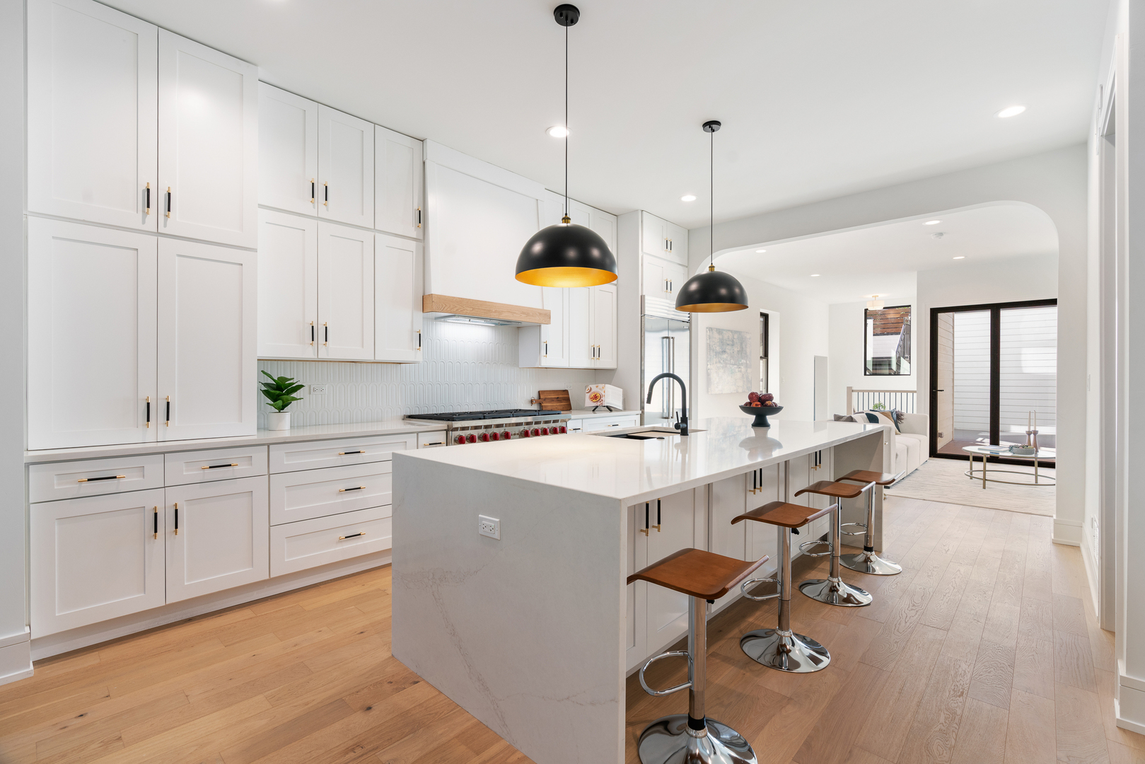 Bright kitchen with white cabinetry, a large island, wood floors, and pendant lights.
