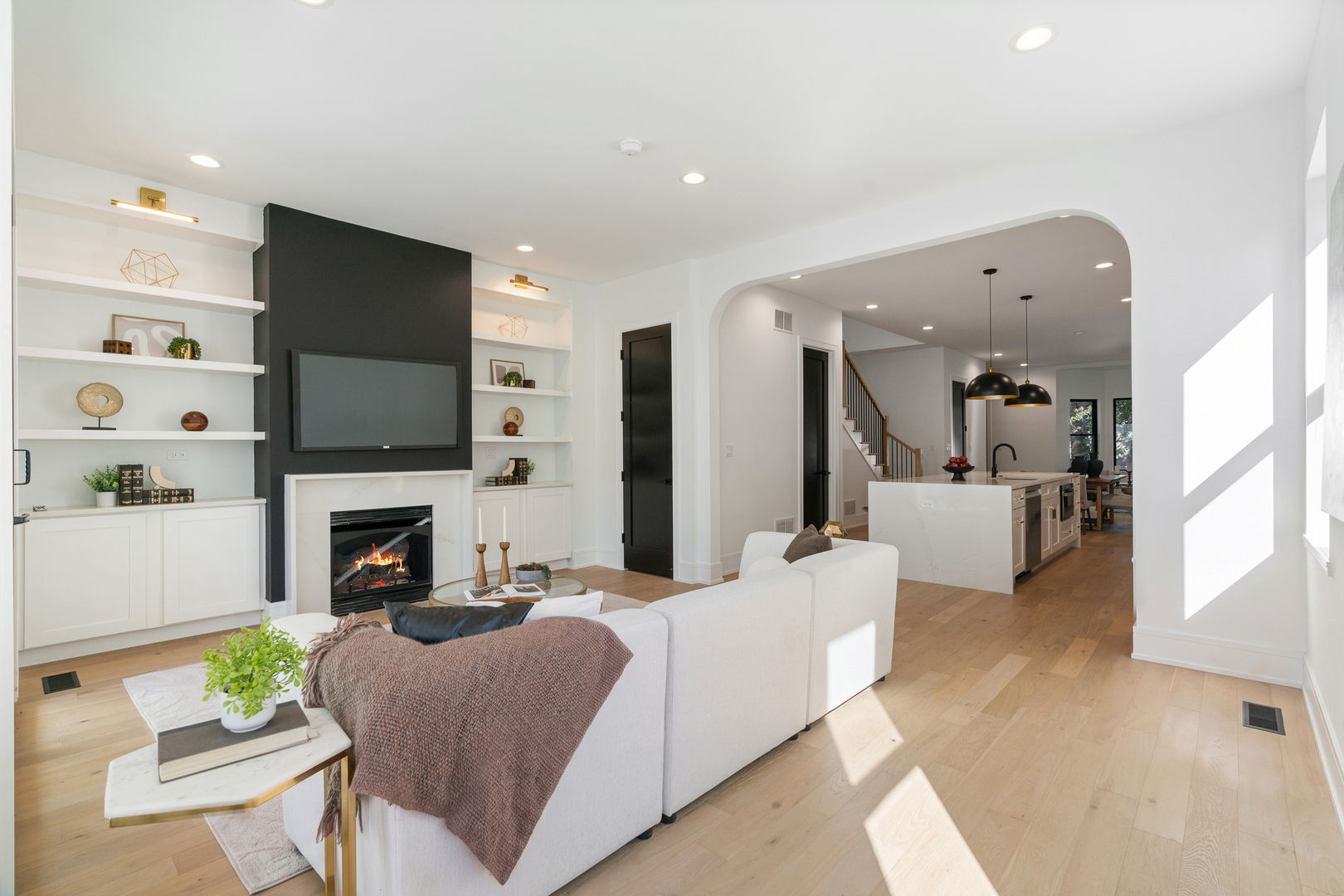 Living room with a fireplace feature wall, built-in shelves, and an open kitchen beyond.