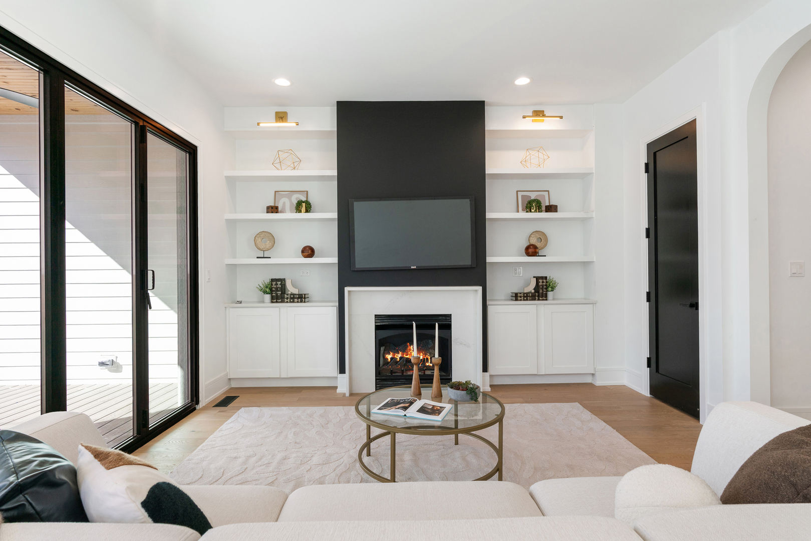 Living room with a fireplace, built-in shelves, and sliding glass doors opening onto a deck.
