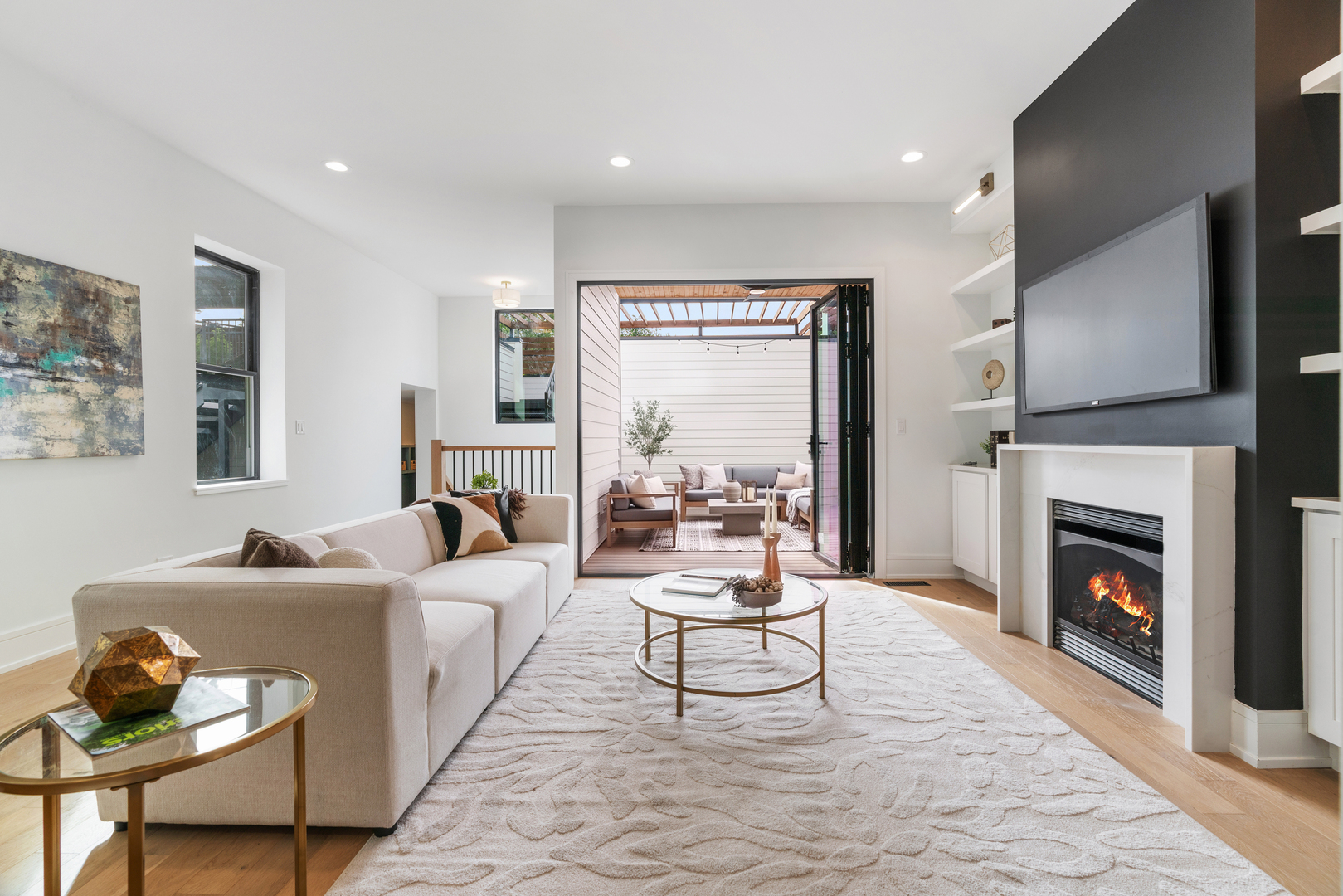 Living room with a sectional sofa, modern fireplace, and open doors to a covered patio.