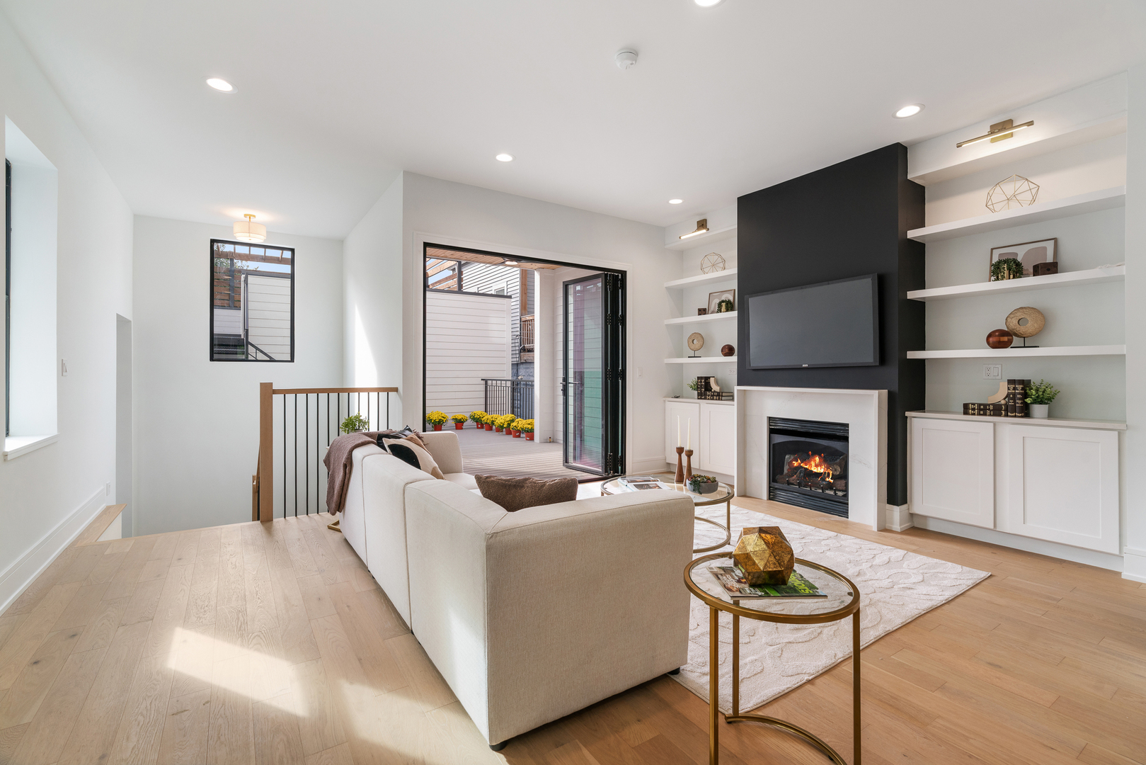 Staged living room with a fireplace, built-in shelving, and open doors to a deck.