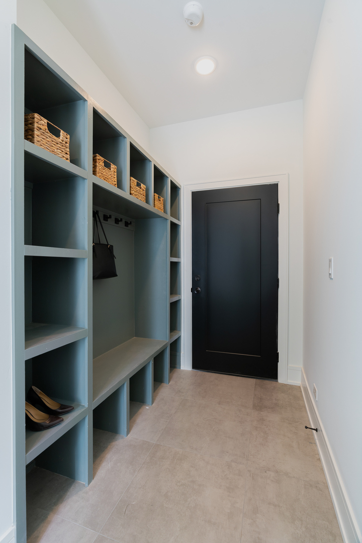 Entryway with blue built-in cubbies, a bench, woven baskets, and a black door.
