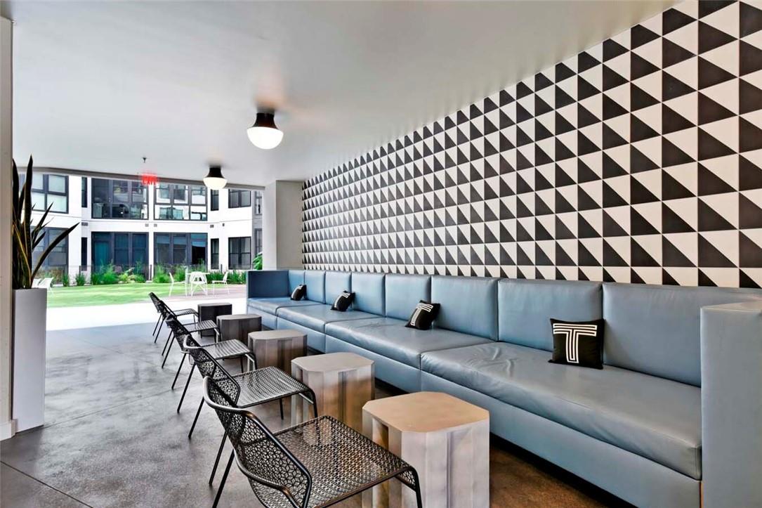 Apartment lounge with a long blue sectional and a black-and-white geometric feature wall.