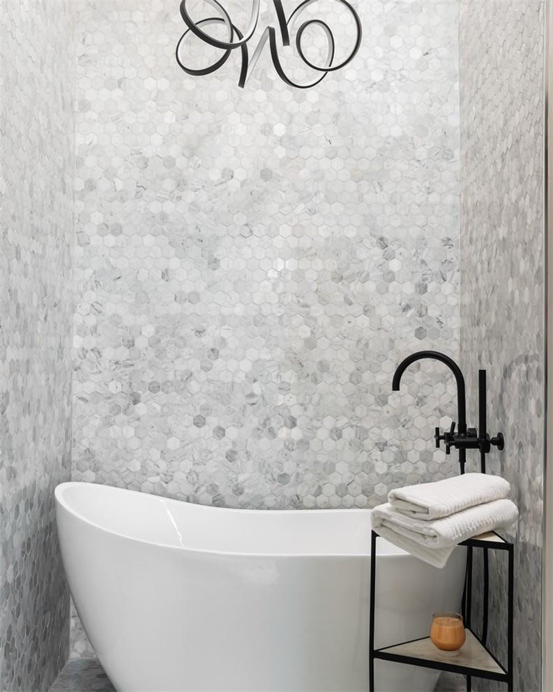 Bathroom with a freestanding tub, hexagonal marble tile, and matte black fixtures.