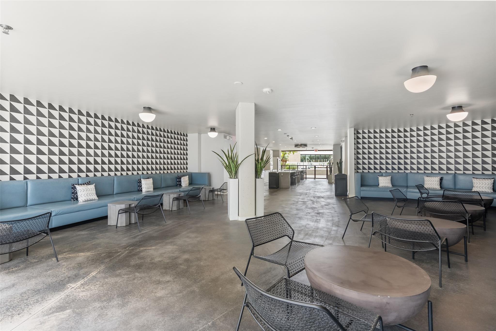 Building lounge with blue sofas, mesh chairs, and geometric black-and-white tile walls.