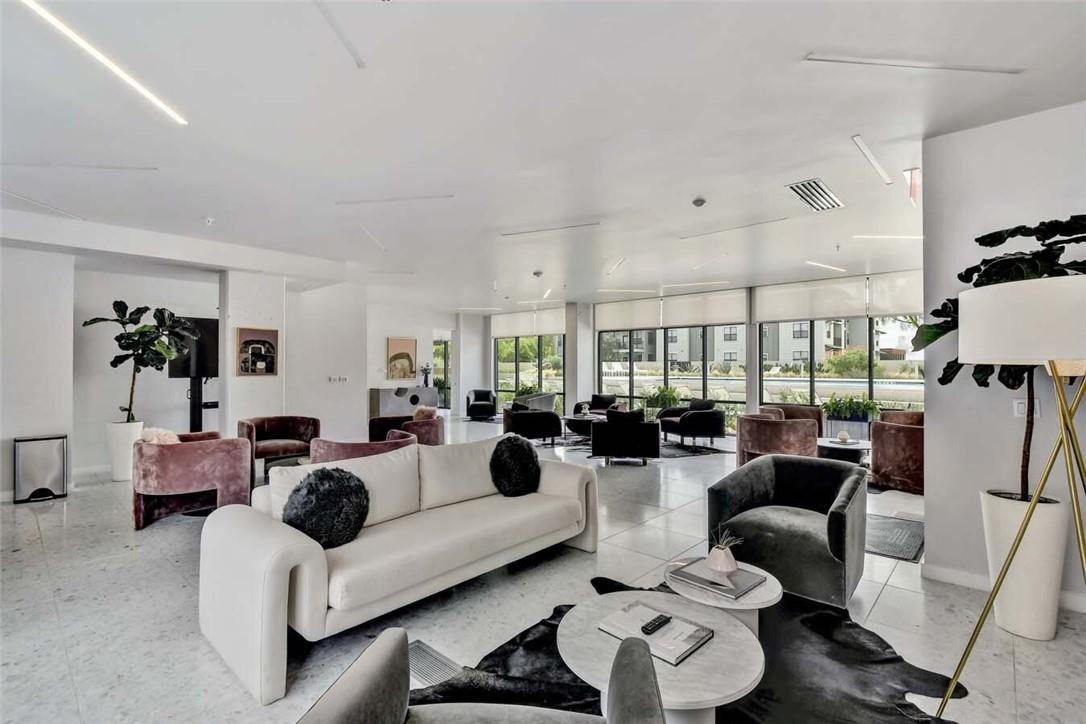 Condo lounge with white sofa, mauve chairs, and floor-to-ceiling windows.