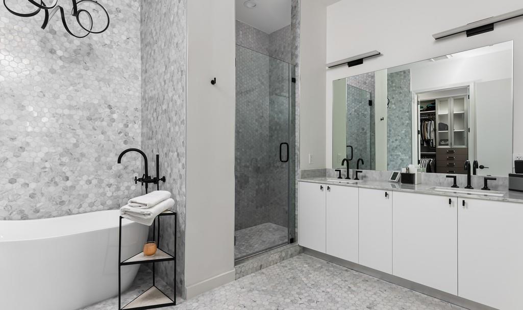 Modern bathroom with a freestanding tub, tiled glass shower, and long white vanity.