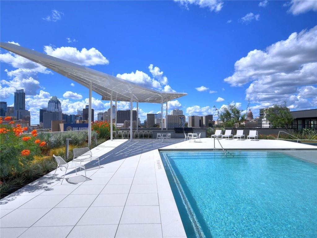 Rooftop pool with a shade canopy and lounge chairs overlooking the Austin skyline.