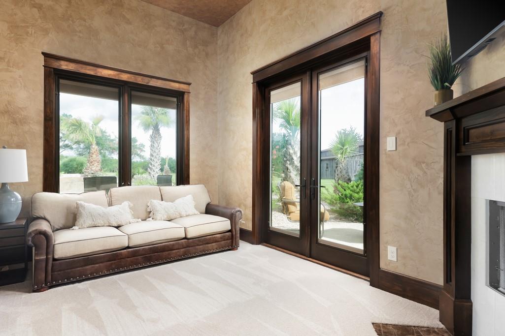 Living room with a cream sofa and tall windows overlooking a landscaped yard.