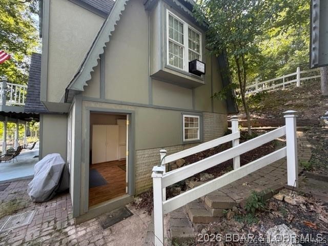 Gray two-story house with an open doorway and white railings along a sloped walkway.