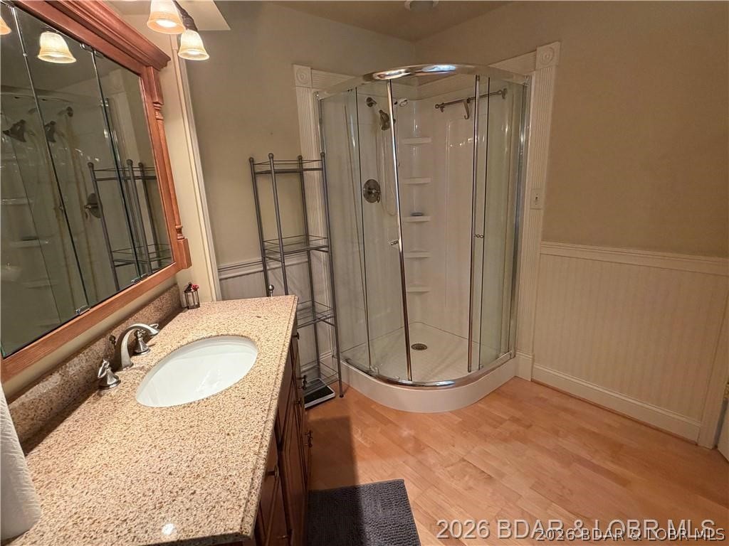 Bathroom with a stone-topped vanity and curved glass corner shower.