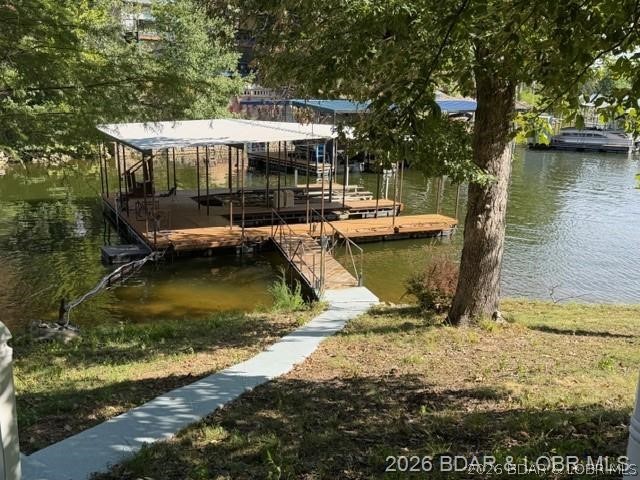 Lakefront dock with covered boat slips and a concrete path leading to the water.
