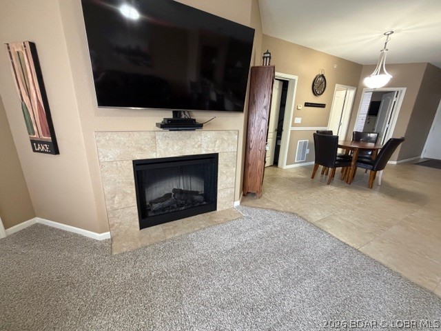 Living and dining area with a tiled fireplace, wall-mounted television, and dining table.