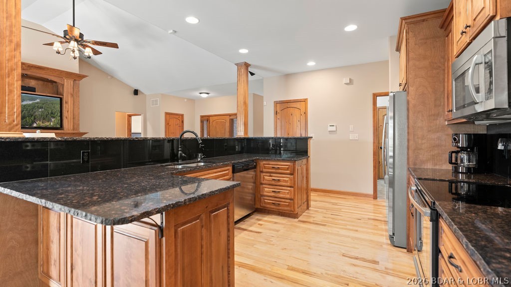 Kitchen with wood cabinets, dark granite counters, and stainless steel appliances.