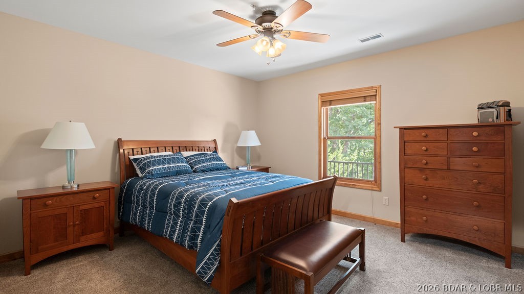 Bedroom with a wooden bed, blue patterned bedding, matching furniture, and a window overlooking greenery.