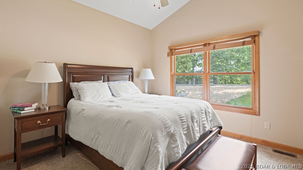 Bedroom with white bedding, dark wood furniture, and a large window overlooking trees.