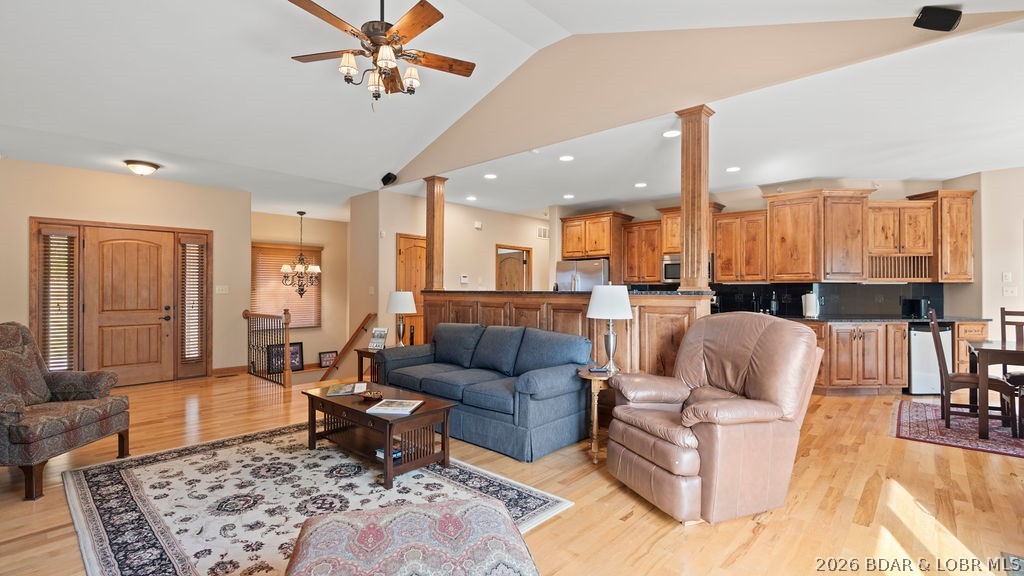 Open-plan living room with blue sofa, leather recliner, hardwood floors, and a wood-cabinet kitchen.