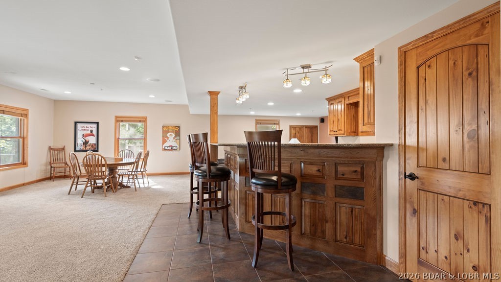 Kitchen and dining area with a wood-paneled bar, granite counter, and dining table.