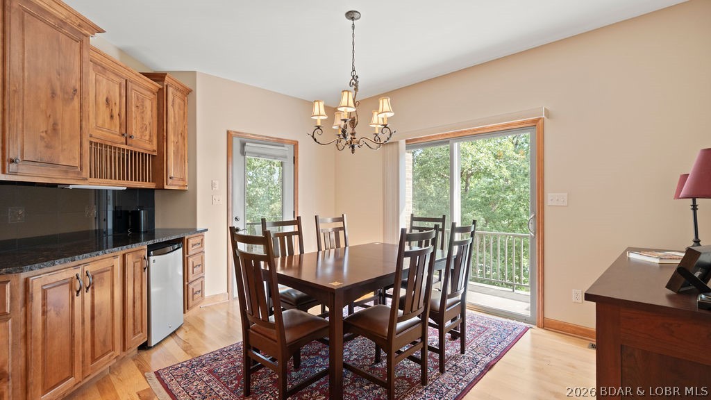 Dining area with a dark wood table, wood kitchen cabinets, and a sliding glass door to a tree-lined deck.
