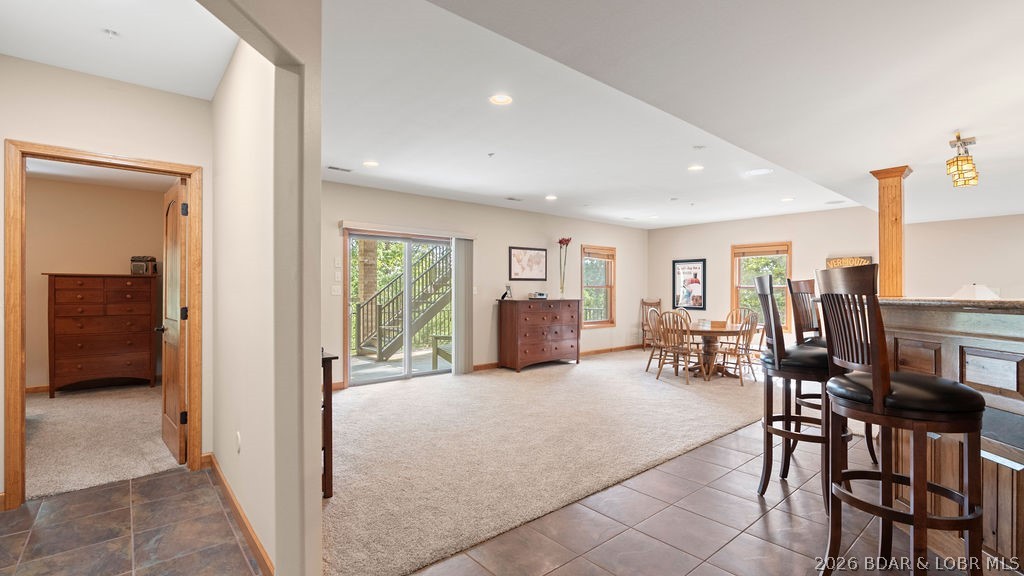 Open dining and kitchen area with a wooden table, counter stools, and sliding glass doors to a deck.