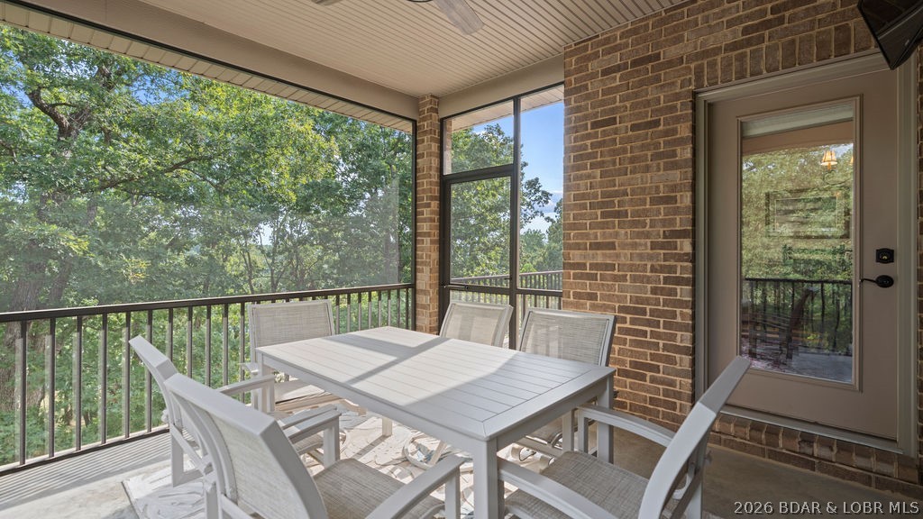 Covered porch with white dining set overlooking leafy trees.