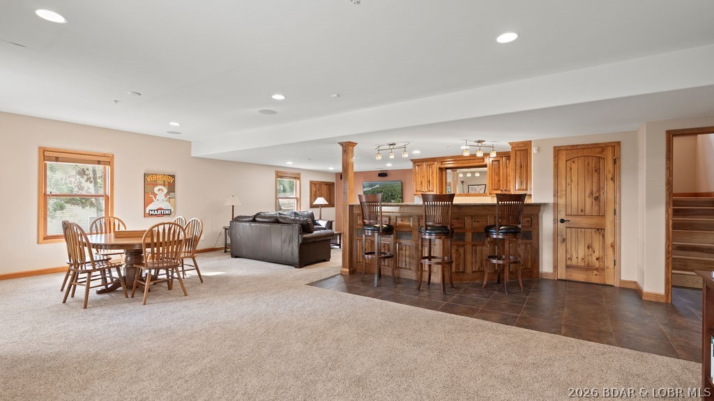 Open-plan living, dining, and kitchen area with wood cabinetry, breakfast bar, and gray sofa.
