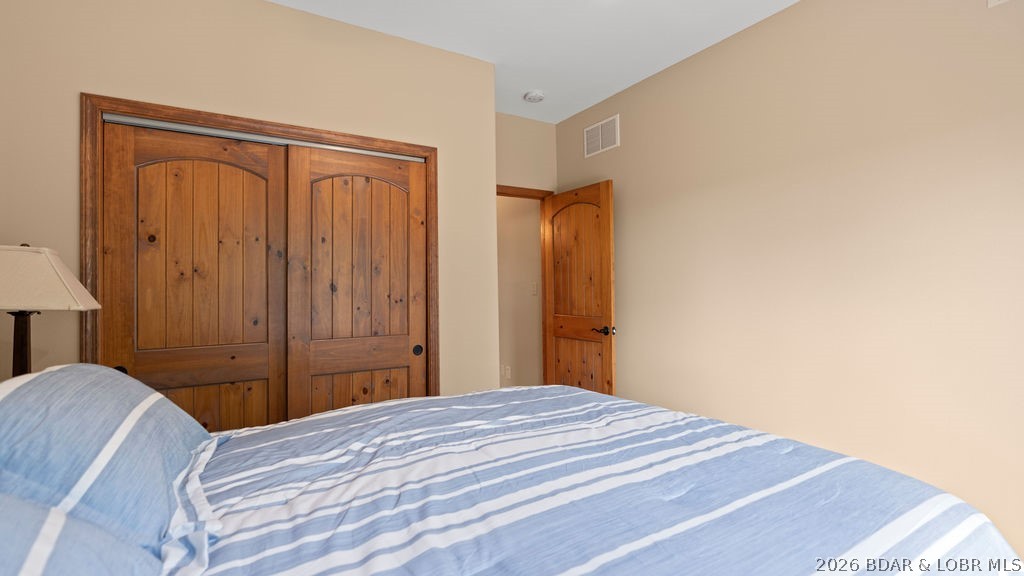 Bedroom with blue striped bedding and rustic wooden closet doors.