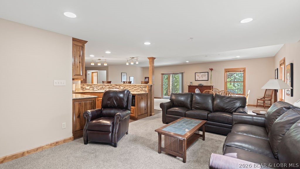 Open-plan living room with dark leather seating, wood coffee table, and kitchen beyond.
