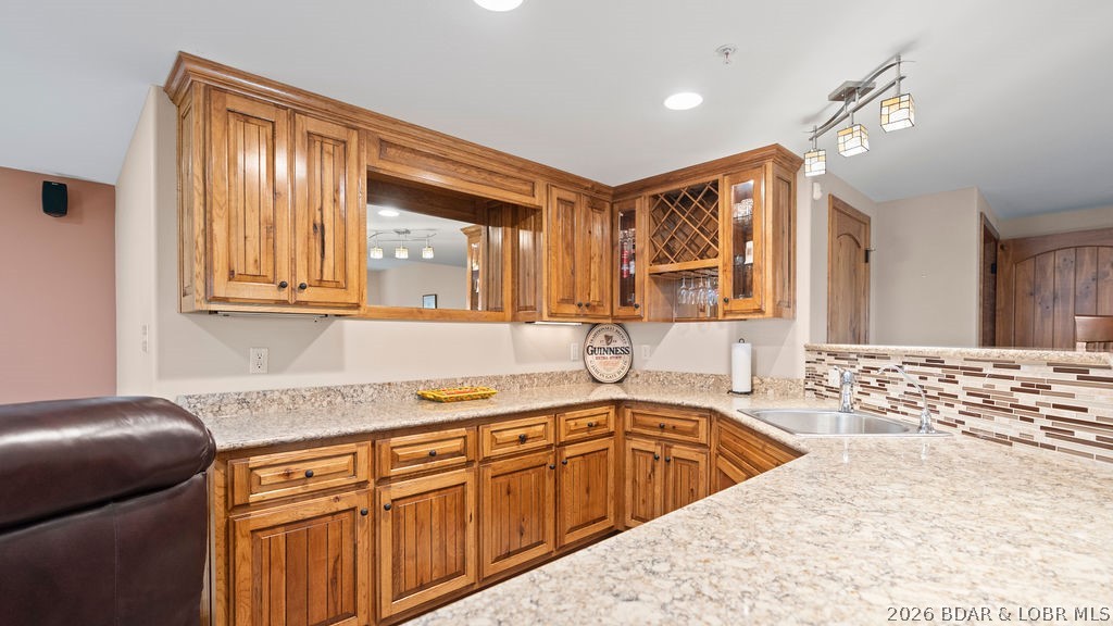 Kitchen with wood cabinetry, granite counters, a built-in wine rack, and a mosaic tile backsplash.