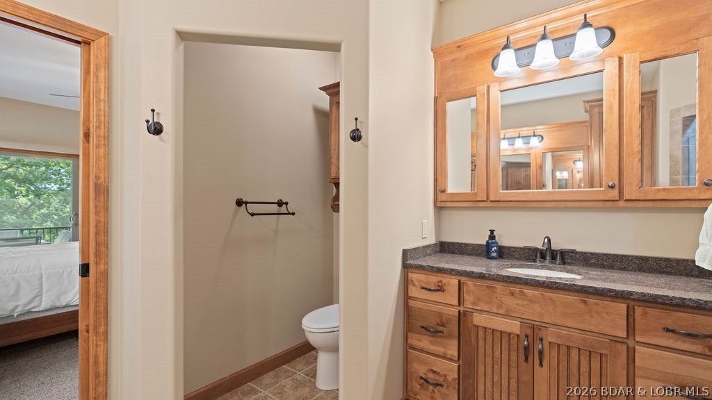 Bathroom with a wood vanity and mirrored cabinet beside a separate toilet alcove.
