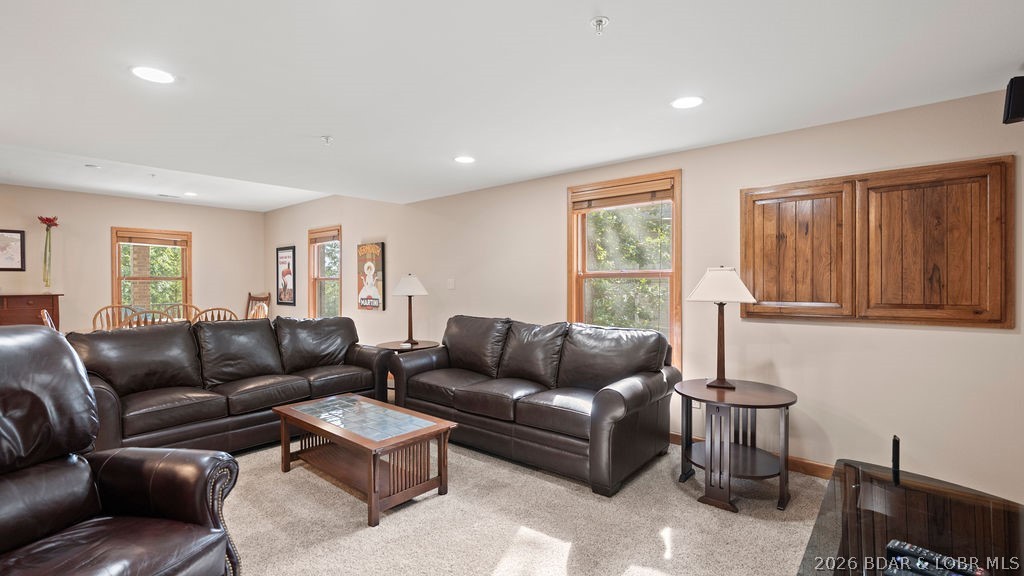 Living room with dark leather sectional, wood coffee table, and built-in wooden cabinets.
