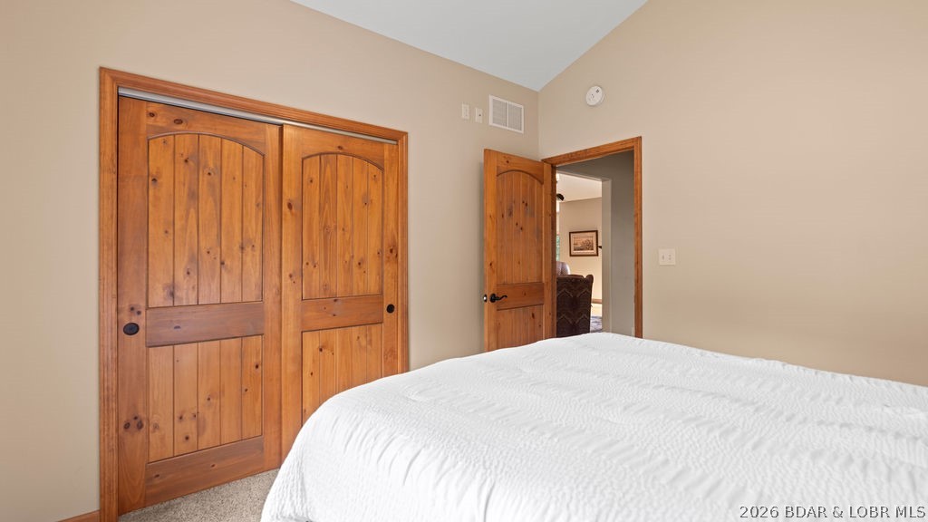 Bedroom with a white quilted bed and rustic wood closet doors.