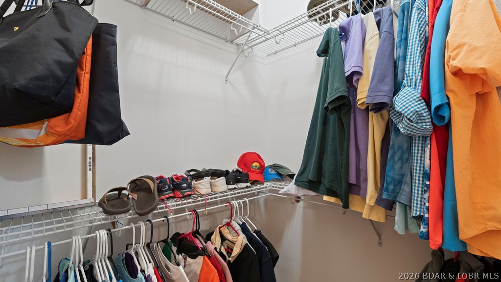 Walk-in closet with wire shelving, hanging clothes, shoes, and bags.