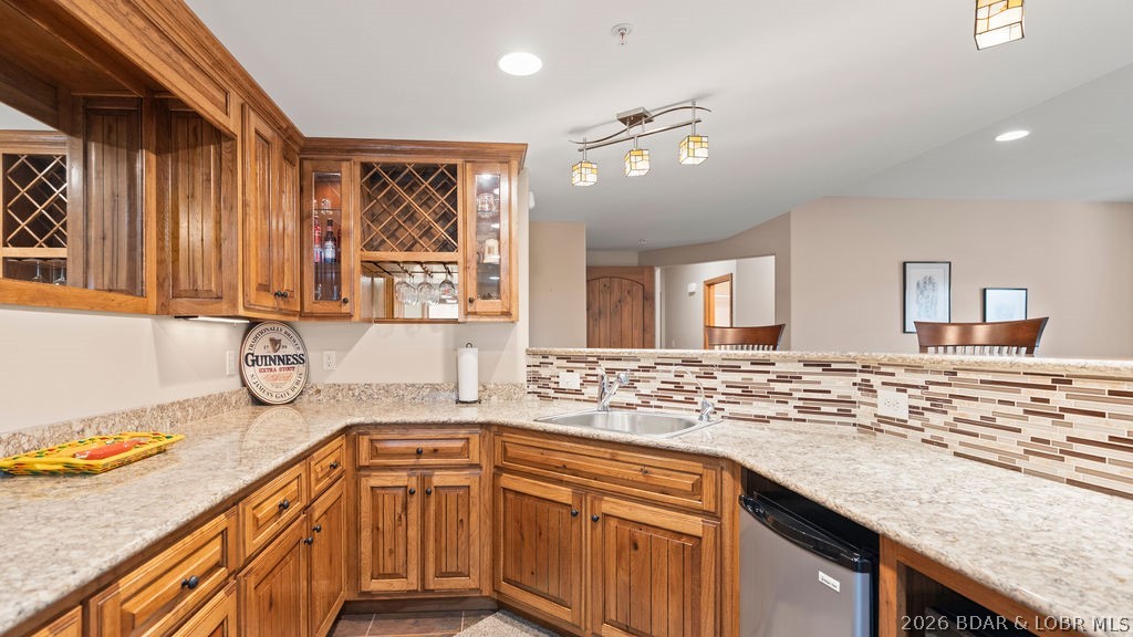 Kitchen with warm wood cabinetry, granite counters, mosaic backsplash, and a breakfast bar.
