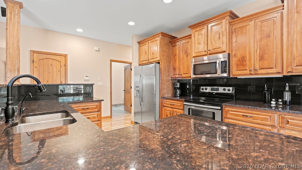 Kitchen with warm wood cabinets, granite counters, stainless steel appliances, and a large sink peninsula.